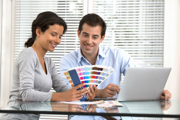 Happy couple choosing colors to paint new house
