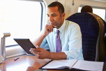 Fototapeta na wymiar Businessman Commuting On Train Using Digital Tablet