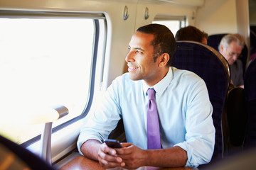 Businessman Commuting To Work On Train Using Mobile Phone - obrazy, fototapety, plakaty