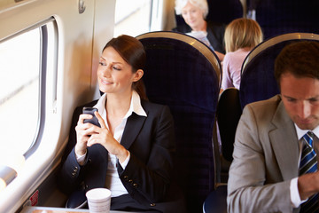 Businesswoman Commuting To Work On Train Using Mobile Phone