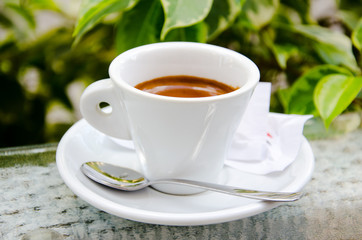 White espresso cup standing on the glass table of street cafe