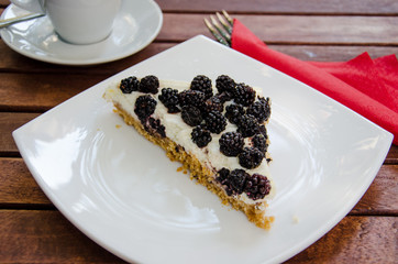 Blackberry cheesecake with coffee standing at the wooden table