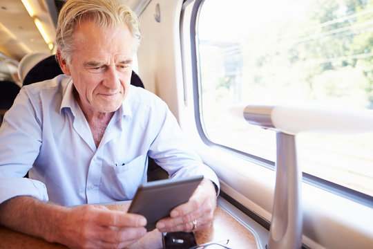 Senior Man Reading E Book On Train Journey
