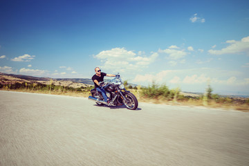 Fototapeta na wymiar Young biker riding a motorcycle on an open road