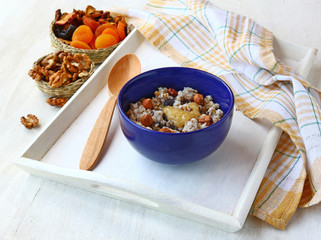A bowl of wheat cereal with nuts, honey, raisins and poppy seeds
