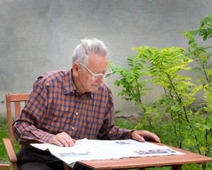 Pensioner reading newspaper in garden