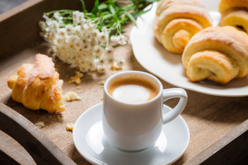 Espresso and croissant for breakfast with flowers