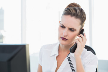 Unsmiling businesswoman talking on the phone