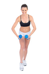 Fototapeta premium Happy sporty brunette exercising with dumbbells