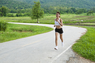 Beautiful Asian woman running on country road.