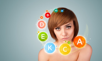 Pretty young girl with colorful vitamin icons and symbols