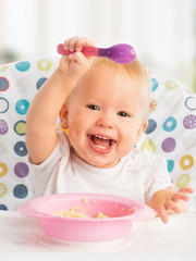 happy baby child eats itself with a spoon © JenkoAtaman