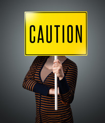 Young woman holding a caution sign