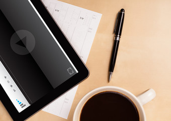 Tablet pc showing media player on screen with a cup of coffee on