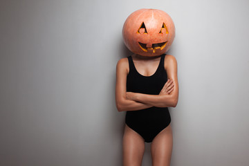 Obraz premium Slim model posing with pumpkin on head. studio