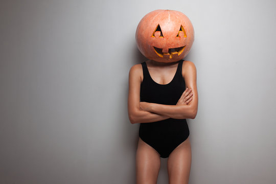 Slim model posing with pumpkin on head. studio