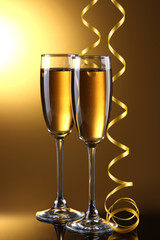 glasses of champagne and streamer on yellow background