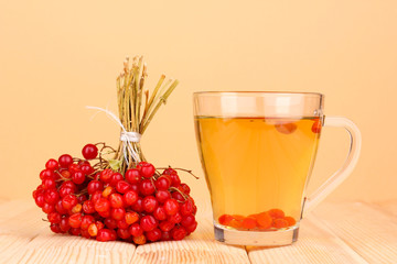 tea with red viburnum on table on beige background