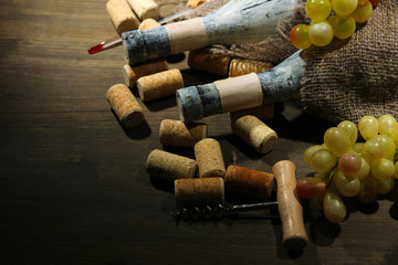 Old bottles of wine, grapes and corks on wooden background