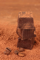 Chopped chocolate with cocoa, on brown background