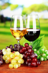 Ripe grapes and glasses of wine, on bright background