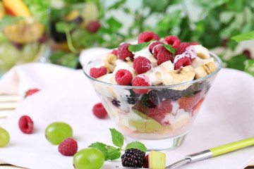 Fruit salad in bowl, on wooden table, on bright background