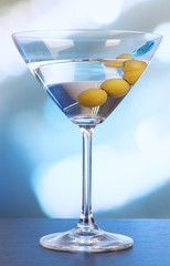 Martini with green olives on table in bar