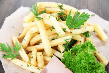 French fries on tracing paper on wooden table