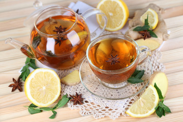 Kettle and cup of tea with ginger on napkin on wooden table
