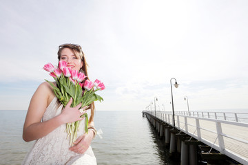 Smiling woman with bunch of flowers sea