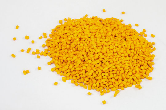 yellow plastic polymer granules on white background