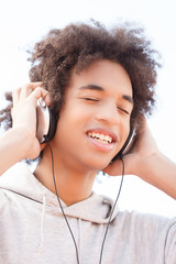 Teenager listening to the music. Cheerful African descent teenag