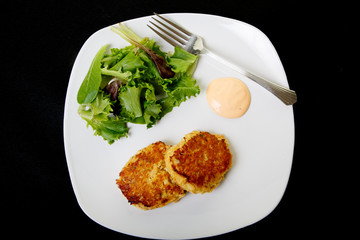 Two Crab Cakes and Salad on Black Background