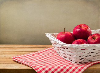 Apple in basket on wooden table with checked tablecloth