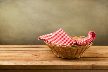 Fototapeta na wymiar Empty basket with checked tablecloth on wooden table
