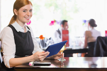 Obraz premium Smiling woman using tablet while holding wine glass and looking