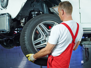 Car mechanic changes car tyres in a garage