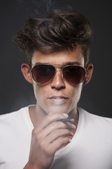 Obraz premium Fashionable young man exhaling cigarette smoke