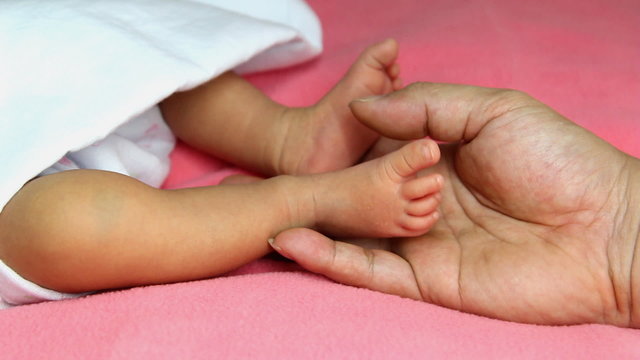 man hand touching on cute newborn baby's feet , one week age
