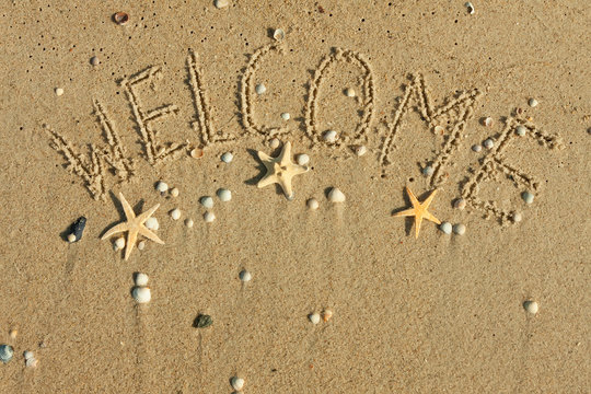 Word welcome written on the sand