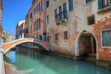 Fototapeta na wymiar Small bridge over canal and old houses in Venice.