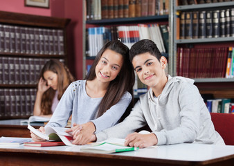 Girlfriend And Boyfriend Holding Hands At Table In School Librar