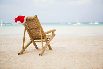 Weihnachtsmütze auf Liegestuhl am weißen Sandstrand