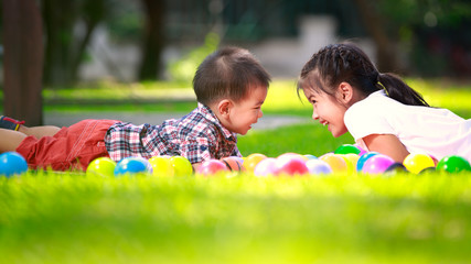 Fototapeta premium Two children are laying on green grass and smile