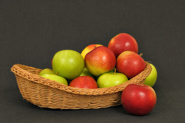 Red and green apples in old village basket