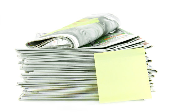 pile of newspaper with yellow stick note isolated on white backg
