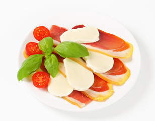 Sliced prosciutto and mozzarella with basil and tomatoes
