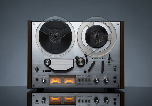 Vintage working analog recorder reel to reel on dark background
