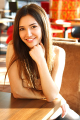 Portrait of beautiful cheerful girl with long brown hair looking
