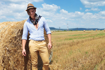Naklejka na ściany i meble casual man posing next to haystack